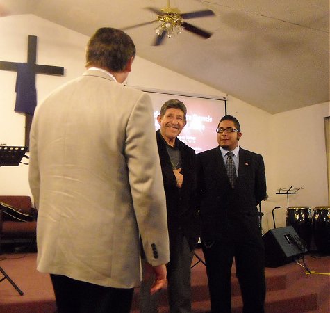 Pastor Miguel López (centro) y su hijo Miguel López Jr. (derecha) recibiendo un elogio del Obispo Paul Holt.